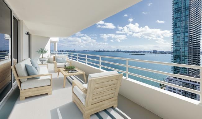 a balcony with a couch and chair overlooking a body of water