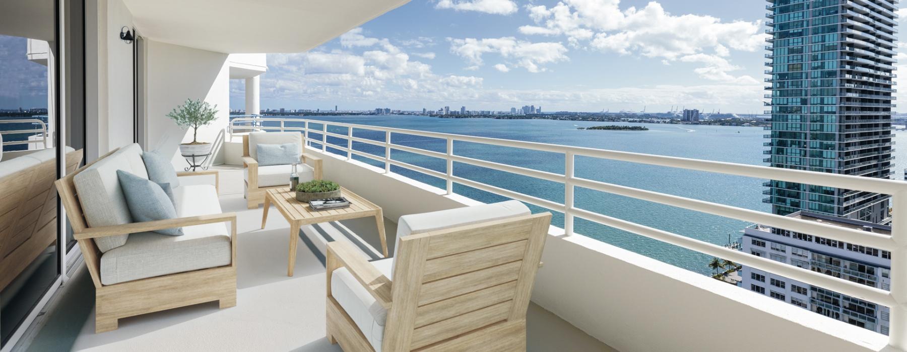 a balcony with a couch and chair overlooking a body of water