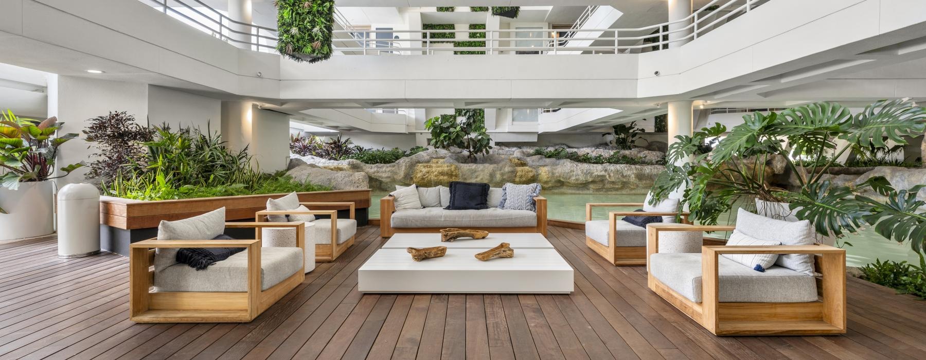 a large room with a wood floor and a couch and chairs surrounded by plants